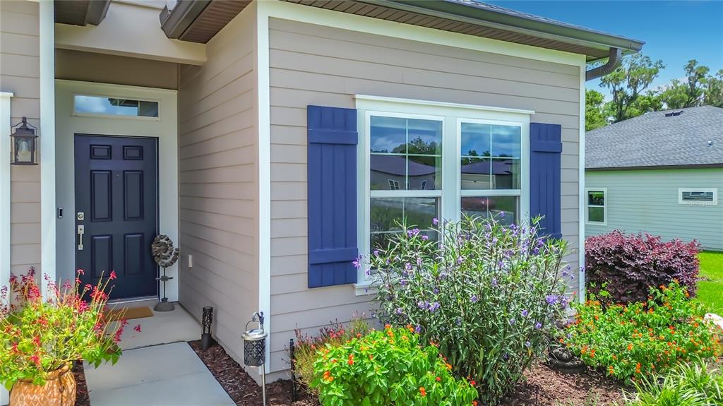 The exterior of a house features a blue front door, blue shutters, and landscaped gardens — 19535 SW 77TH LOOP, DUNNELLON, FL