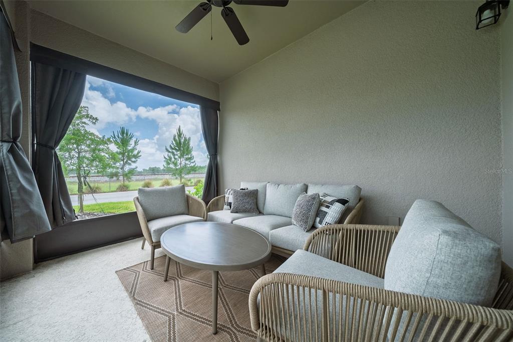 A covered patio features outdoor furniture, a ceiling fan, and a view of a grassy area — 11404 SUNSAIL AVENUE, ORLANDO, FL