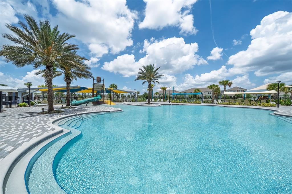 A large swimming pool with a water slide and palm trees under a cloudy sky — 11404 SUNSAIL AVENUE, ORLANDO, FL