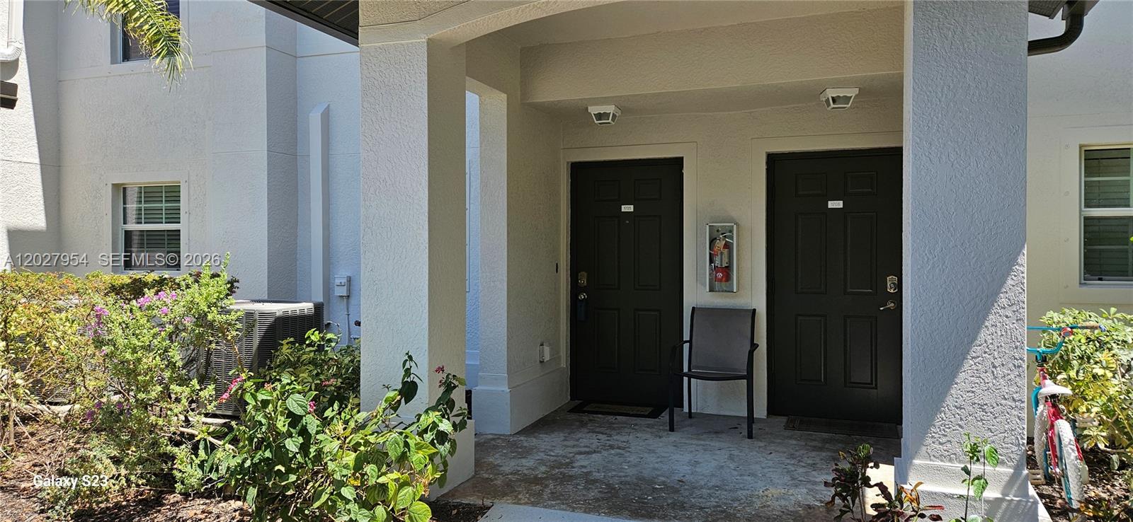 The exterior entrance features two dark doors, a fire extinguisher, and a small patio area — 9101 Gervais Cir. # 1705, Naples FL 34120, NAPLES, FL