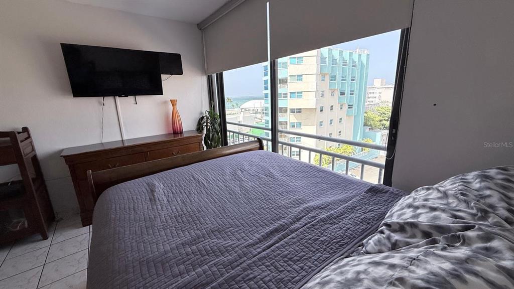 A bedroom features a bed, a wooden dresser with a television, and a balcony view — 37 ISLA VERDE AVE, CAROLINA, PR
