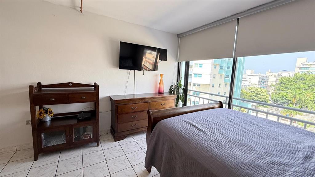 A bedroom features a bed, wooden furniture, a wall-mounted television, and a large window — 37 ISLA VERDE AVE, CAROLINA, PR
