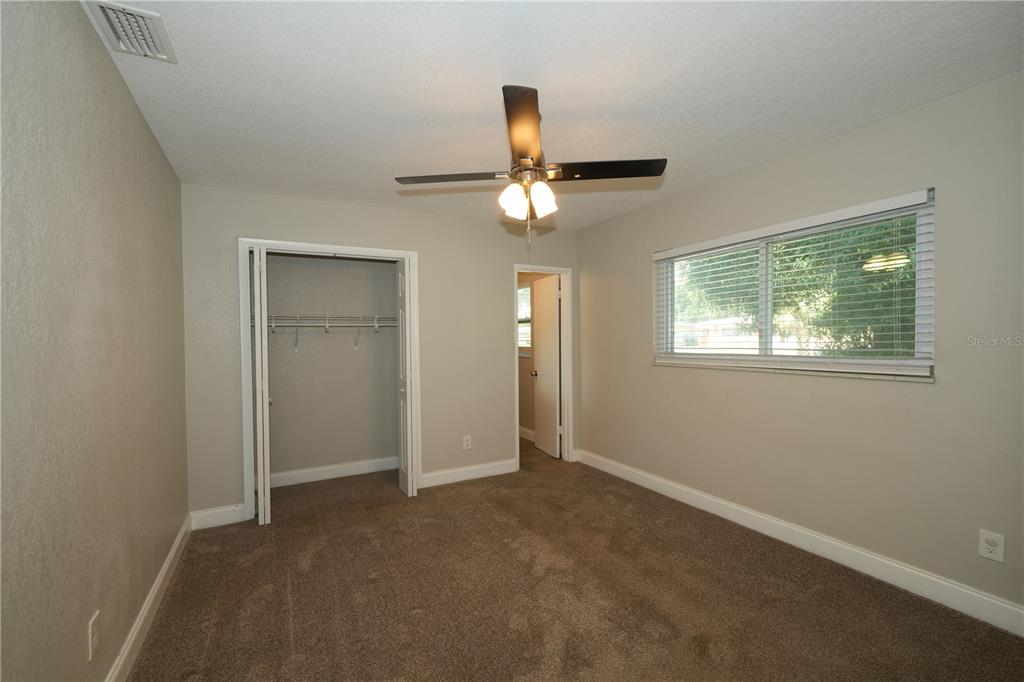 An empty bedroom features beige walls, brown carpeting, a ceiling fan, and a closet — 4517 S CLARK AVENUE, TAMPA, FL