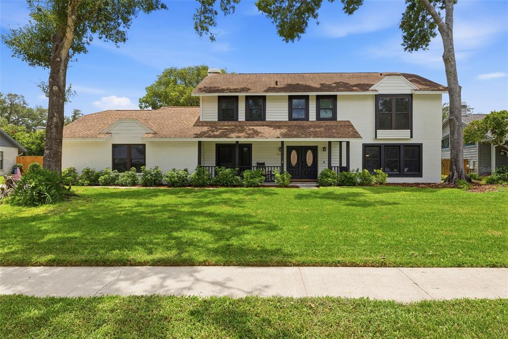 A two-story white brick house with a brown shingled roof and dark window trim — 11007 THERESA ARBOR DRIVE, TAMPA, FL
