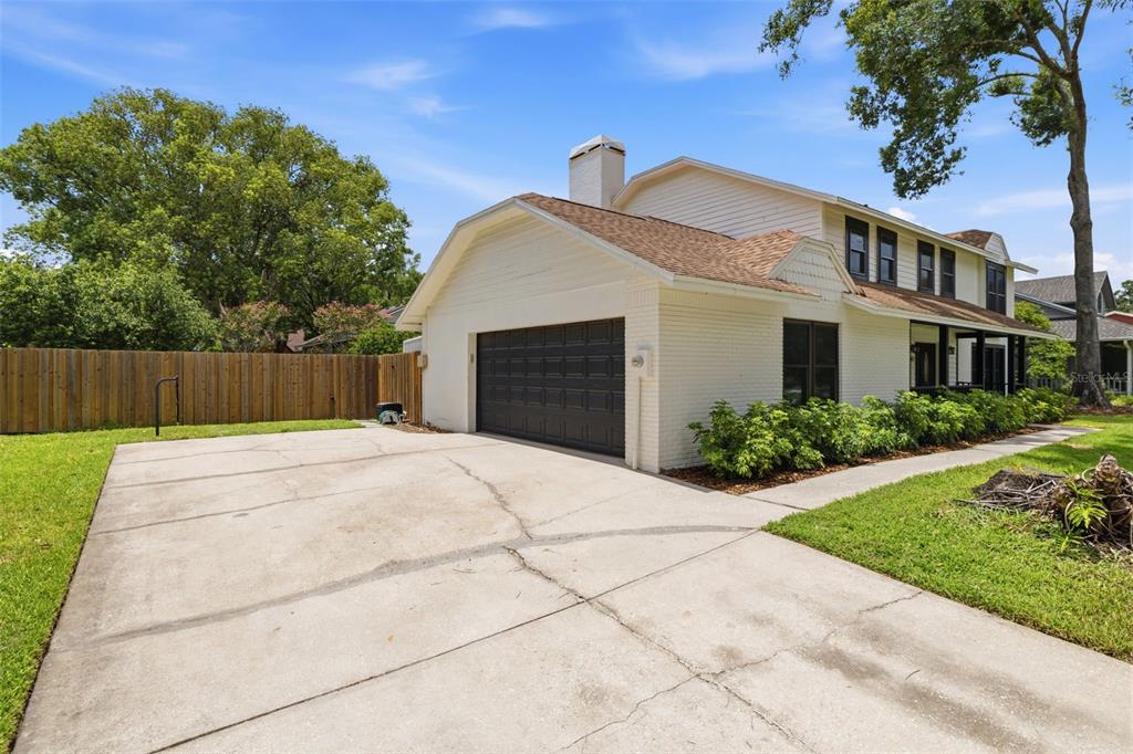 A white brick house with a two-car garage and a concrete driveway under a blue sky — 11007 THERESA ARBOR DRIVE, TAMPA, FL
