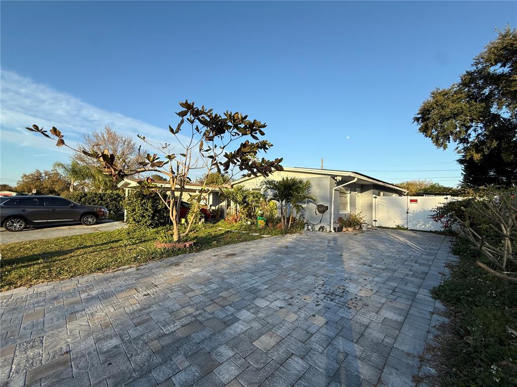 A single-story house with a paved driveway, a carport, and a white privacy fence — 2615 N BEAUMONT AVENUE, KISSIMMEE, FL