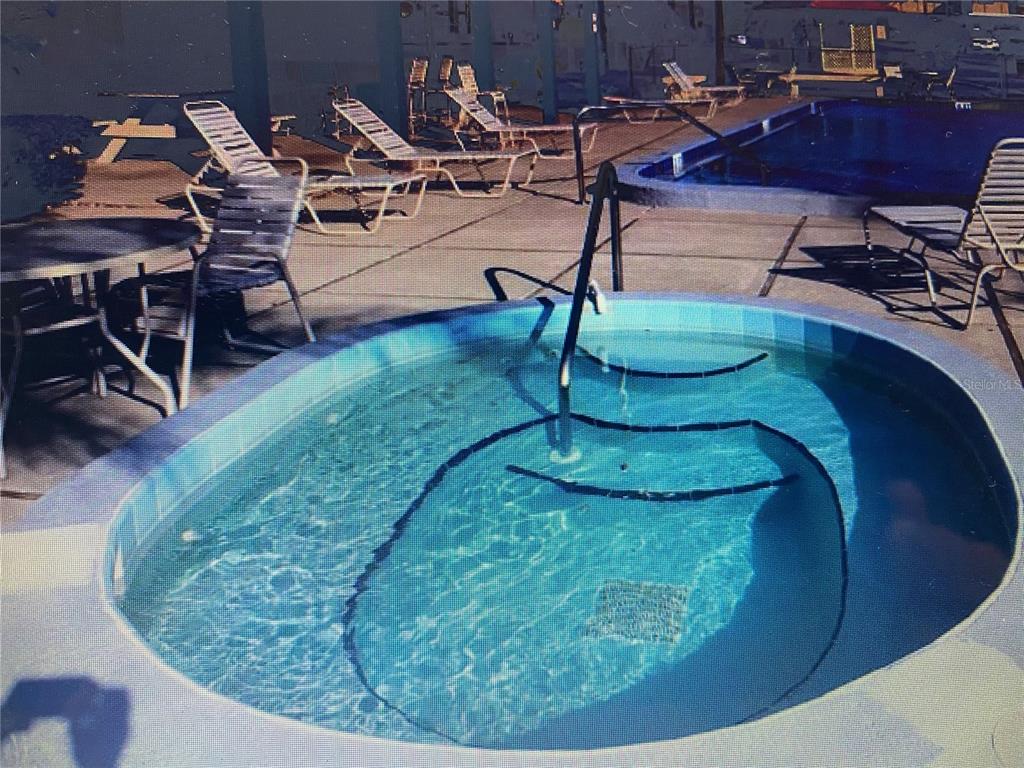 A circular hot tub sits on a concrete pool deck surrounded by lounge chairs — 2440 WINDING CREEK BOULEVARD UNIT 108, CLEARWATER, FL
