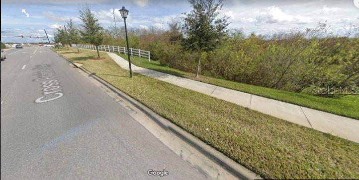 A paved sidewalk runs alongside a road next to a grassy area with a white fence — NEPTUNE ROAD, KISSIMMEE, FL