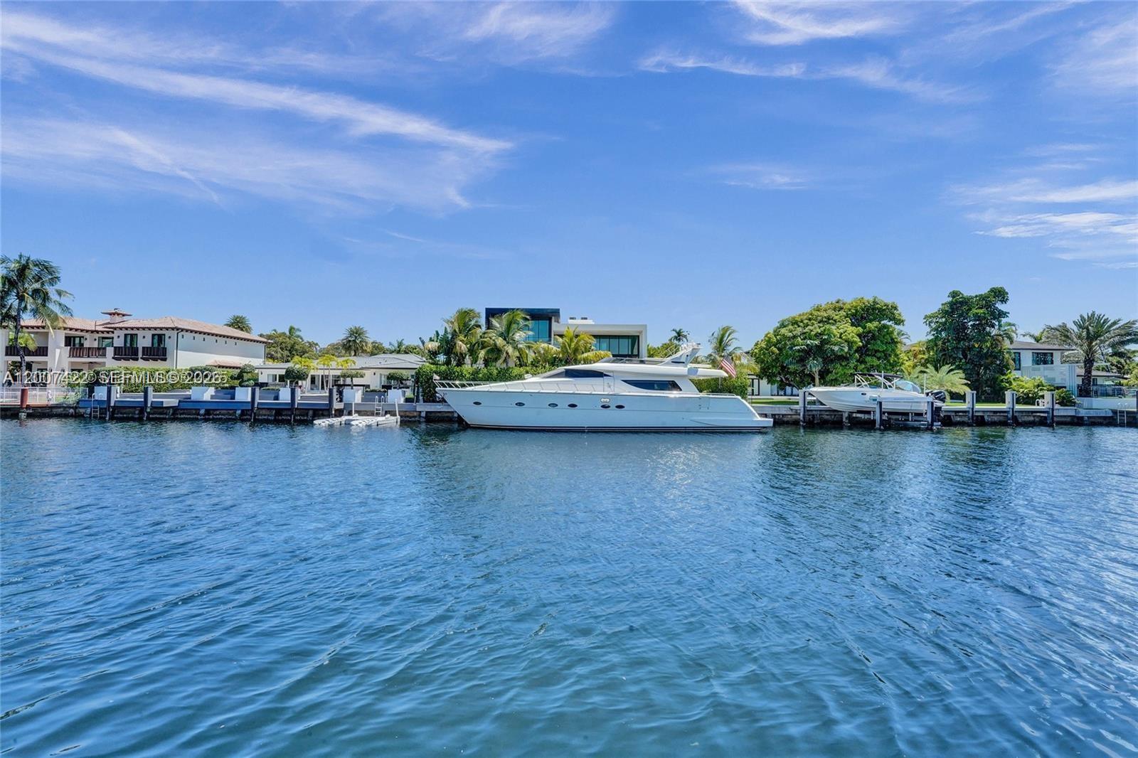 A screened-in patio features a tiled table overlooking a canal with two docked yachts — 455 Paradise Isle Blvd # 104, Hallandale Beach FL 33009, HALLANDALE BEACH, FL