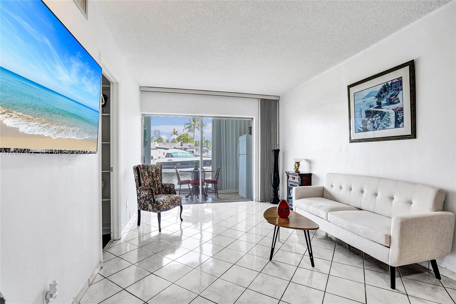 A living and dining area features white tile floors, a white sofa, and a fireplace — 455 Paradise Isle Blvd # 104, Hallandale Beach FL 33009, HALLANDALE BEACH, FL