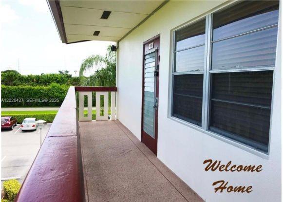 An outdoor balcony with a red railing overlooks a parking lot with two cars — 449 Fanshaw K # 449, Boca Raton FL 33434, BOCA RATON, FL