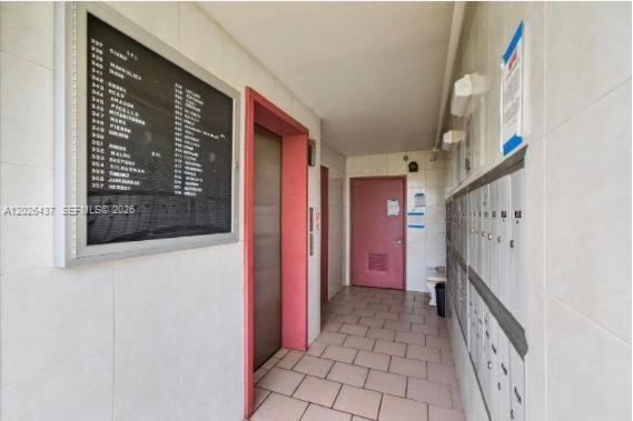 A hallway features a directory board, an elevator, a red door, and wall-mounted mailboxes — 449 Fanshaw K # 449, Boca Raton FL 33434, BOCA RATON, FL