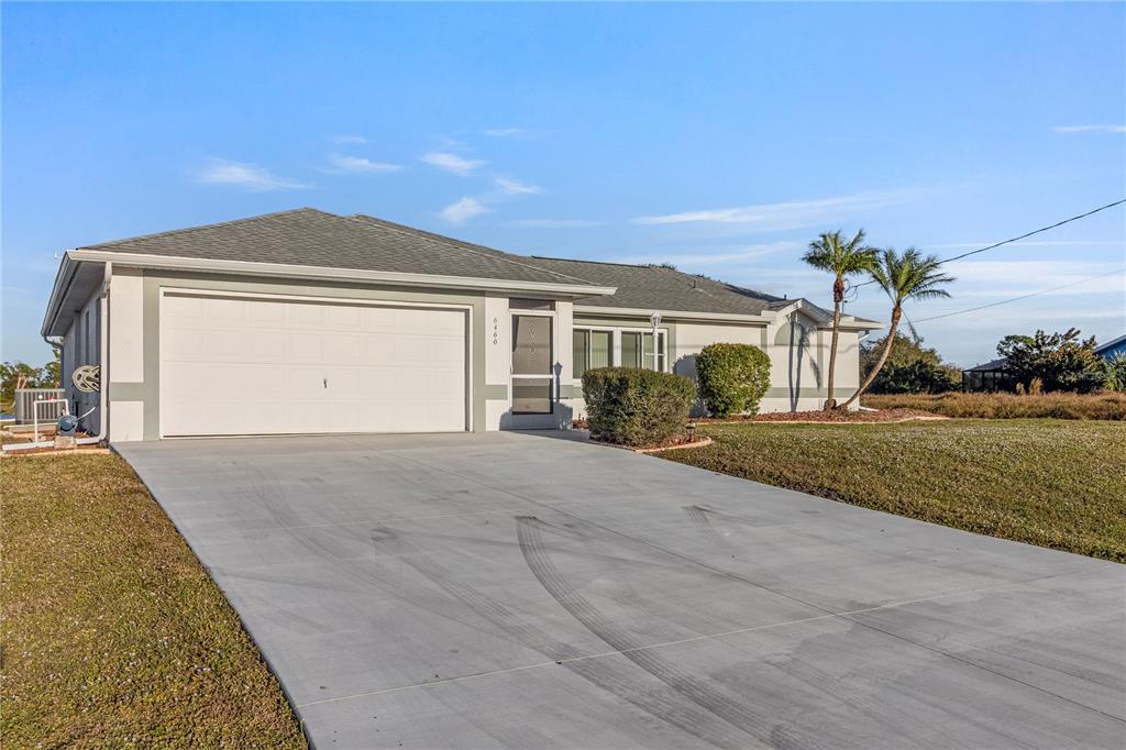A single-story house with a white garage door, gray trim, and a concrete driveway — 6460 BLUEBERRY DRIVE, ENGLEWOOD, FL