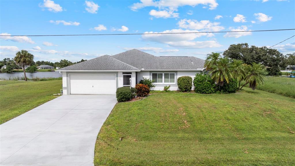 A single-story house with a white garage, gray roof, and a large front lawn — 6460 BLUEBERRY DRIVE, ENGLEWOOD, FL