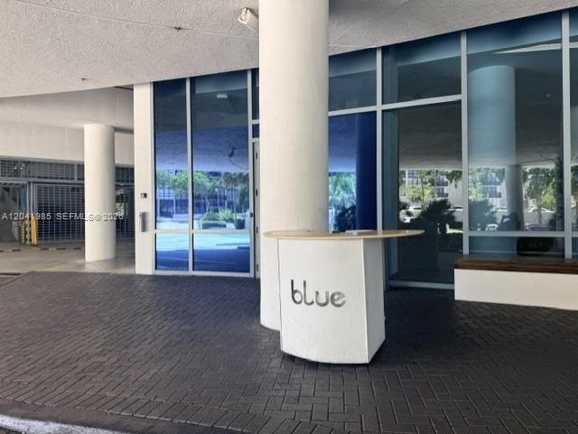 A covered outdoor entrance features a white concierge desk labeled blue on a brick driveway — 601 NE 36th St # 803, Miami FL 33137, MIAMI, FL
