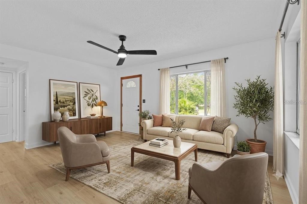 A living room features light wood flooring, a beige sofa, two armchairs, and a ceiling fan — 6206 S FOSTER AVENUE, TAMPA, FL