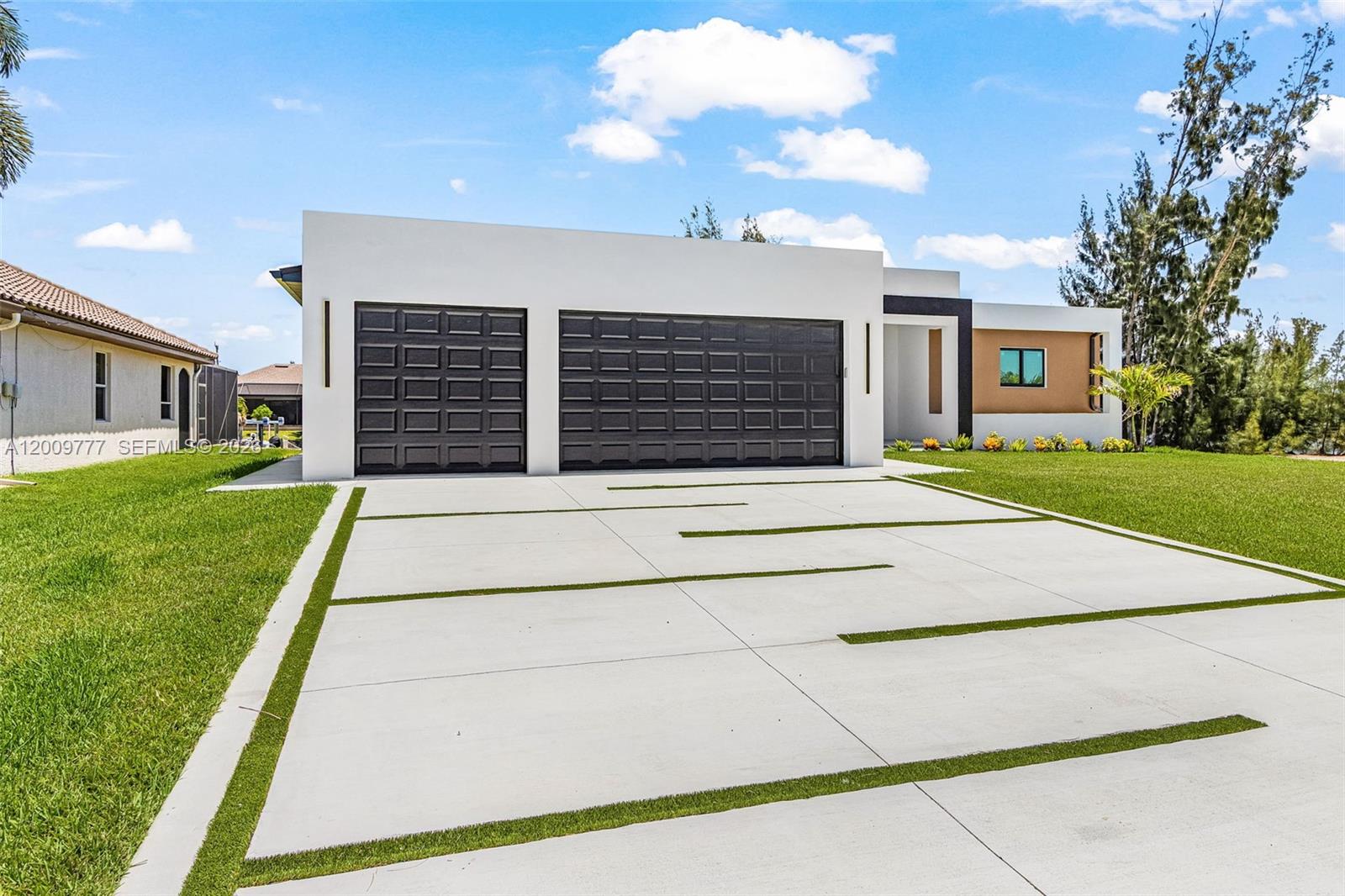 A modern single-story house features a three-car garage and a concrete driveway with grass strips — 2303 NW 35 AVE, Cape Coral FL 33993, CAPE CORAL, FL