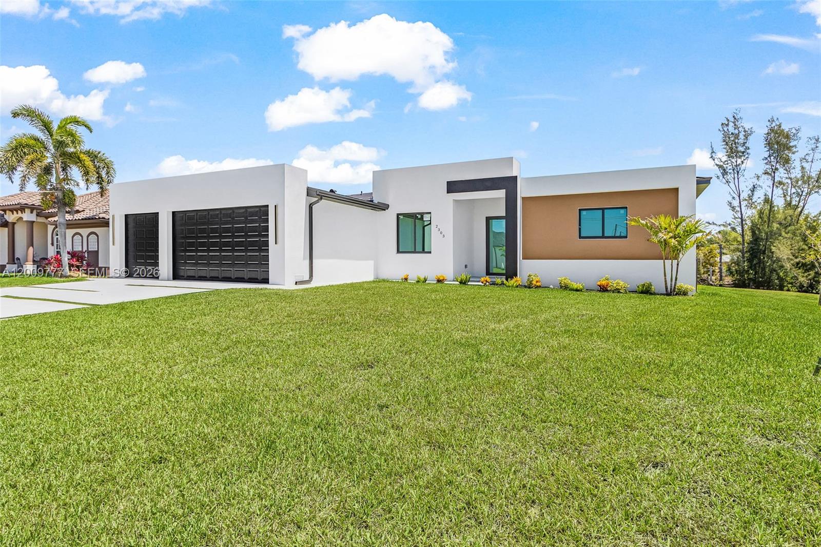 A modern, single-story white house with a black garage door and a tan accent wall — 2303 NW 35 AVE, Cape Coral FL 33993, CAPE CORAL, FL