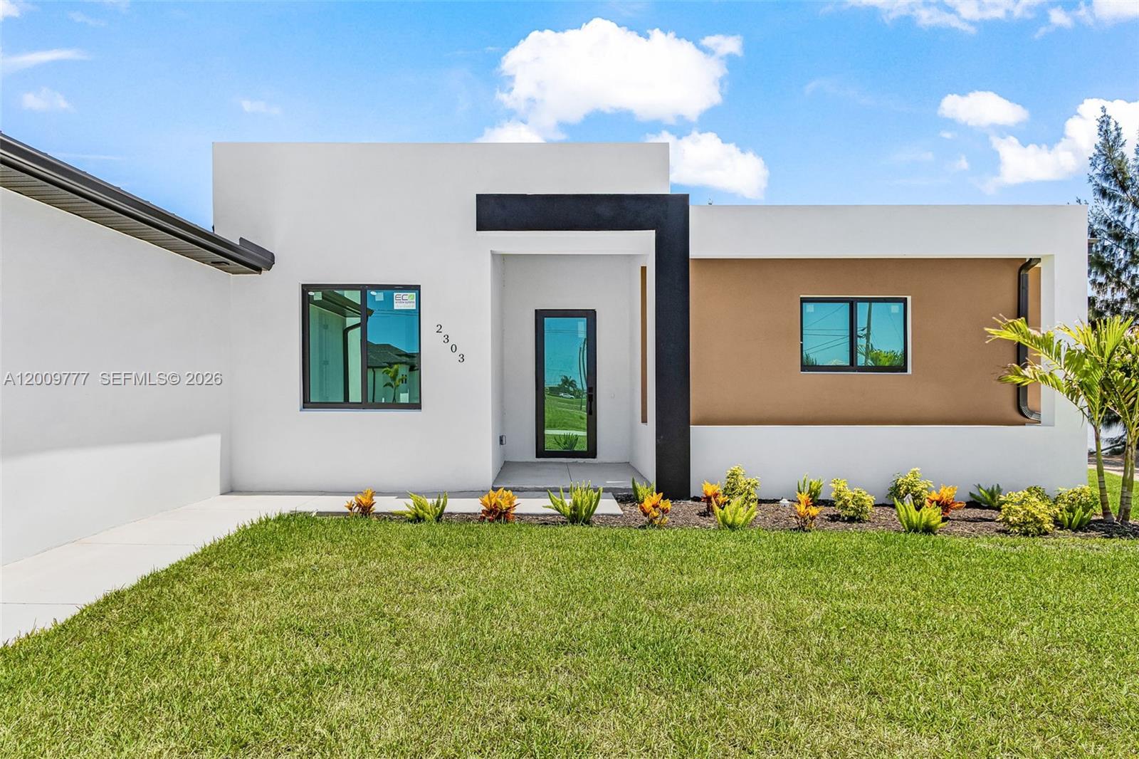 A modern, single-story house features white and tan stucco walls with a black entryway frame — 2303 NW 35 AVE, Cape Coral FL 33993, CAPE CORAL, FL