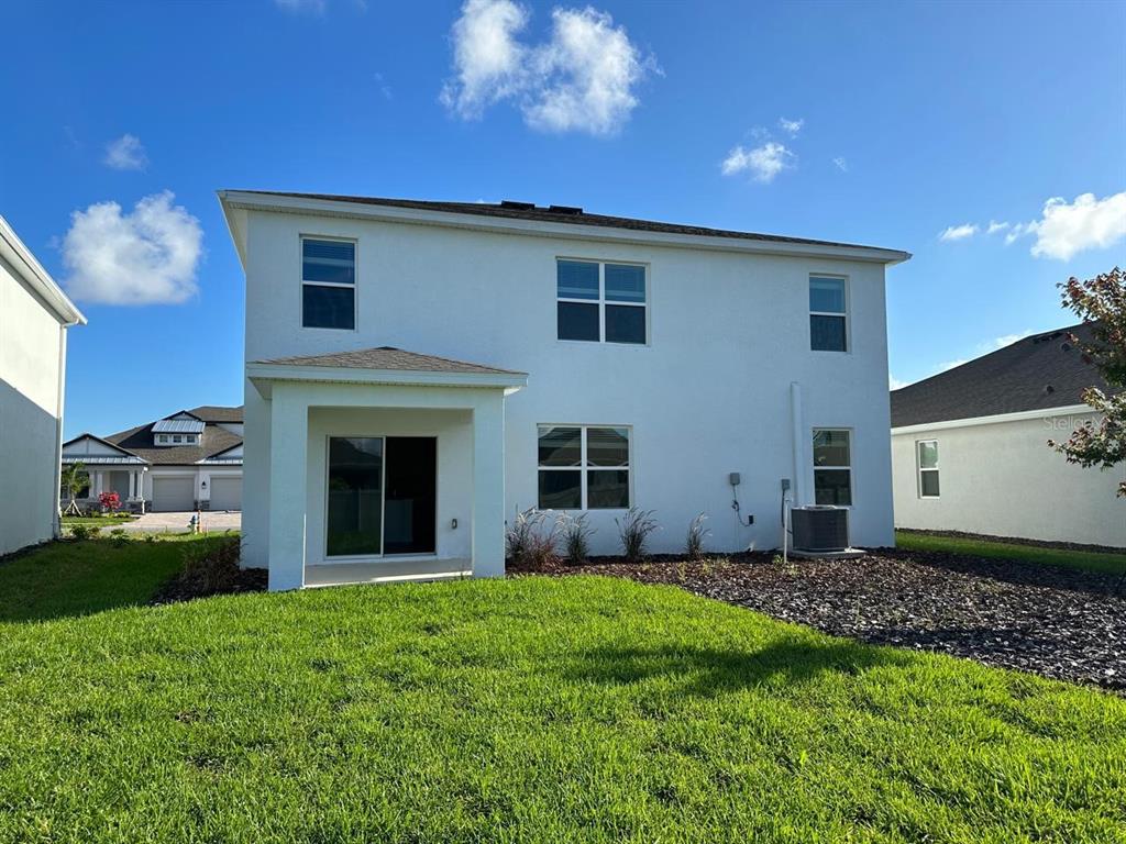 The rear exterior of a two-story white house features a covered patio and lawn — 12760 LATERAL ROOT DRIVE, SARASOTA, FL