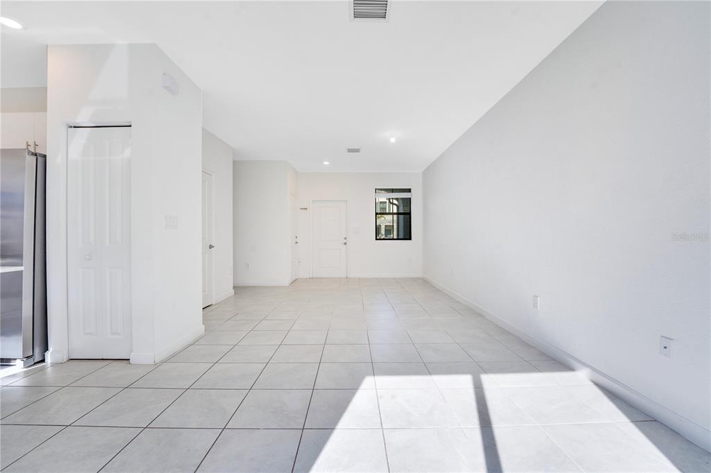 An empty room features white walls, light-colored tile flooring, a window, and a white door — 28517 SW 134TH AVENUE, HOMESTEAD, FL