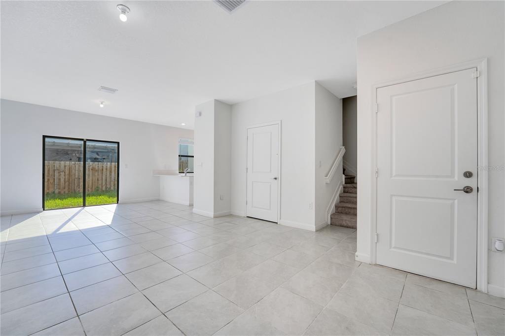 A bright, open-concept living area features white tile flooring, a staircase, and sliding glass doors — 28517 SW 134TH AVENUE, HOMESTEAD, FL