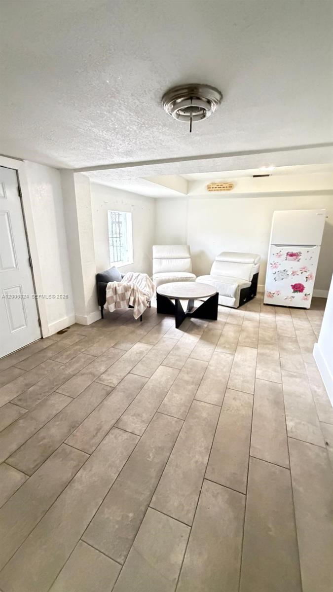 A room with light-colored tile flooring, white walls, a ceiling light, and a white refrigerator — 301 NW 37th St, Miami FL 33127, MIAMI, FL