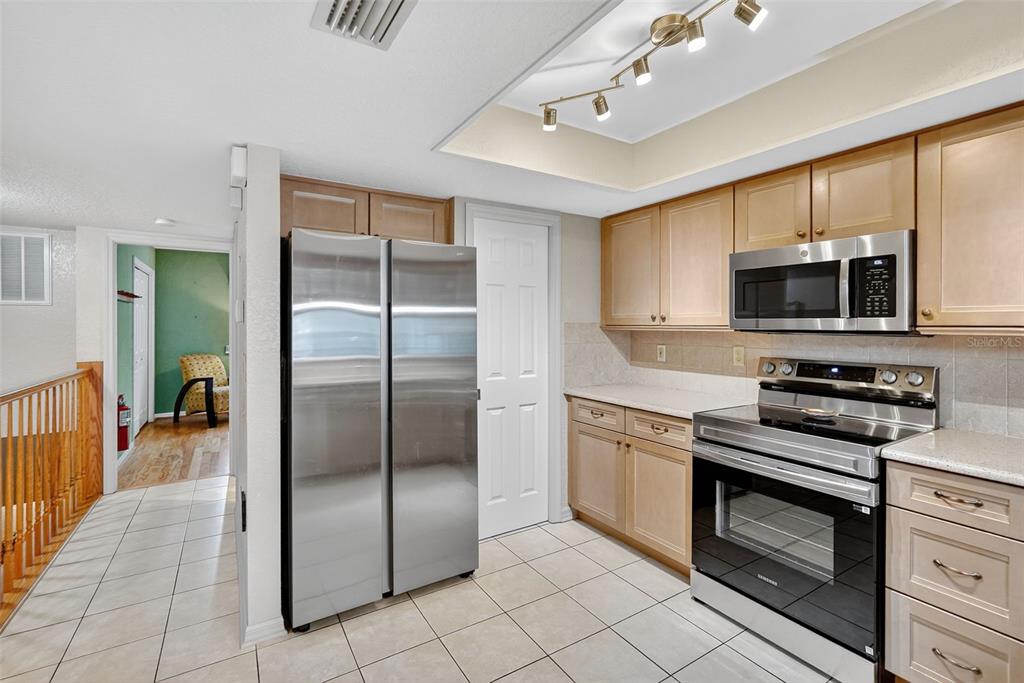 A kitchen features light wood cabinets, stainless steel appliances, and tile flooring — 14879 SEMINOLE TRAIL, SEMINOLE, FL