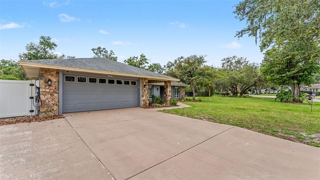 A single-story house features a gray garage door, stone accents, and a concrete driveway — 5776 DEER FLAG DRIVE, LAKELAND, FL