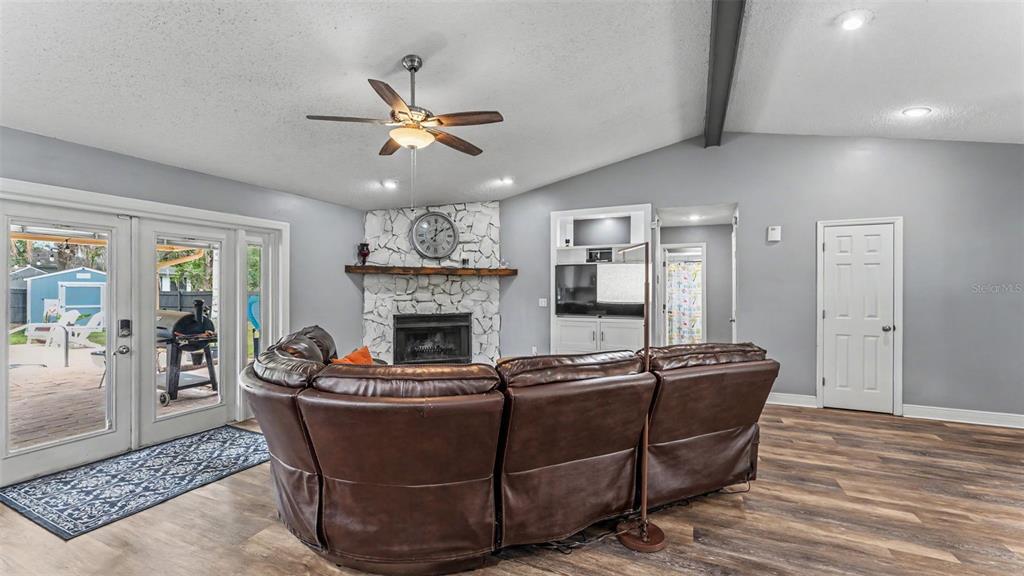 A living room features a stone fireplace, a brown leather sectional, and glass patio doors — 5776 DEER FLAG DRIVE, LAKELAND, FL