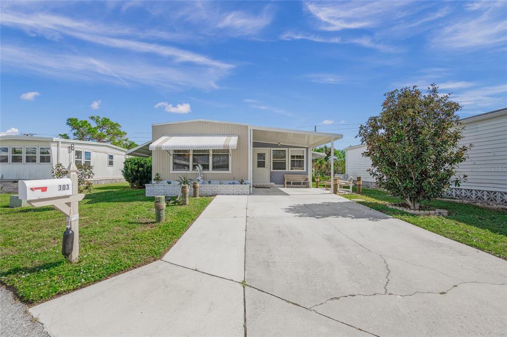 A single-story manufactured home with a concrete driveway, carport, and a white mailbox — 303 MARLETTE DRIVE, NORTH PORT, FL