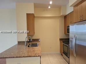A kitchen features granite countertops, light wood cabinets, and stainless steel appliances — 1830 Radius Dr # 1218, Hollywood FL 33020, HOLLYWOOD, FL