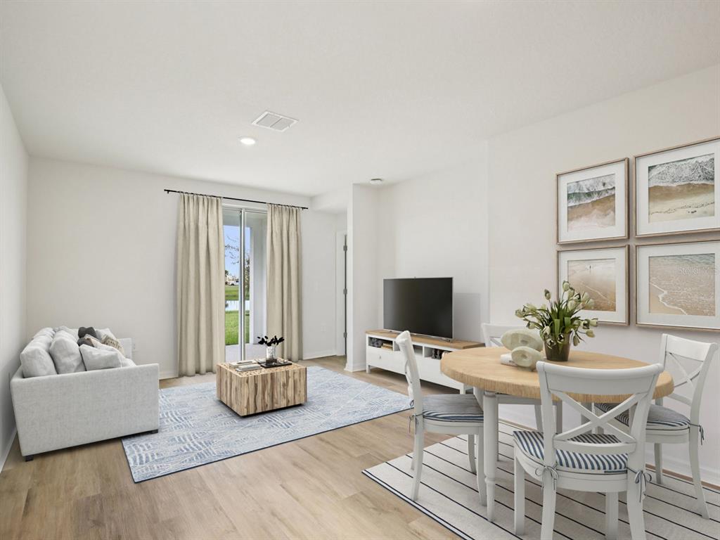 A living and dining area with light wood floors, a sofa, and a round table — 161 CANOE BEND AVENUE, NOKOMIS, FL