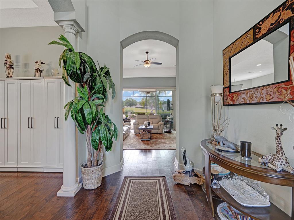 An entryway with hardwood floors leads through an arched doorway to a living room — 13422 NITI DRIVE, HUDSON, FL