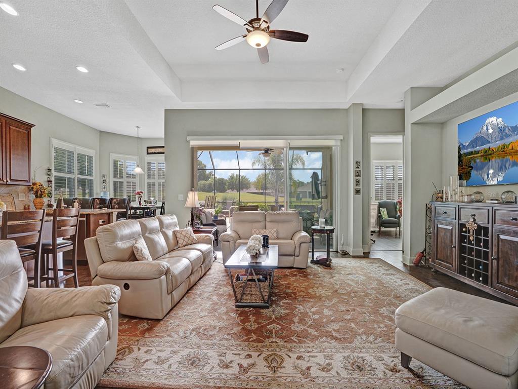 A living room with a tray ceiling, leather sofas, and a view of a screened lanai — 13422 NITI DRIVE, HUDSON, FL
