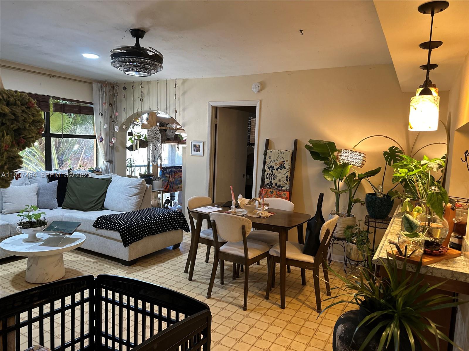 A living and dining area features a sectional sofa, a wooden table, and many plants — 2480 W 67th Pl # 12, Hialeah FL 33016, HIALEAH, FL
