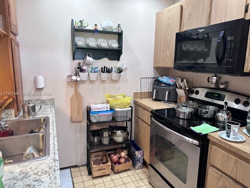 A kitchen features wood cabinets, a stainless steel stove, and a metal storage rack — 2480 W 67th Pl # 12, Hialeah FL 33016, HIALEAH, FL