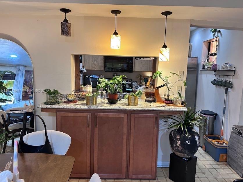 A kitchen pass-through window features a granite countertop, wooden cabinets, and three pendant lights — 2480 W 67th Pl # 12, Hialeah FL 33016, HIALEAH, FL