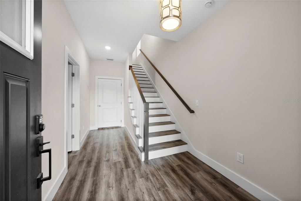 A bright entryway features wood-look flooring, a staircase with a dark railing, and a pendant light — 3122 W AZEELE STREET UNIT 3, TAMPA, FL