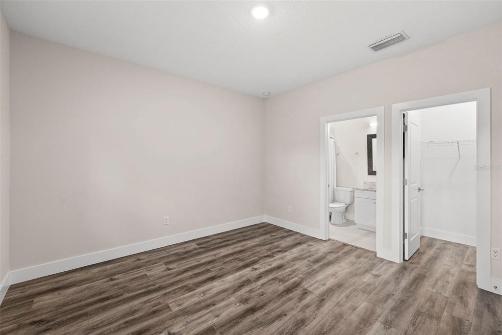 A bedroom with light-colored walls, wood-look flooring, an attached bathroom, and a walk-in closet — 3122 W AZEELE STREET UNIT 3, TAMPA, FL