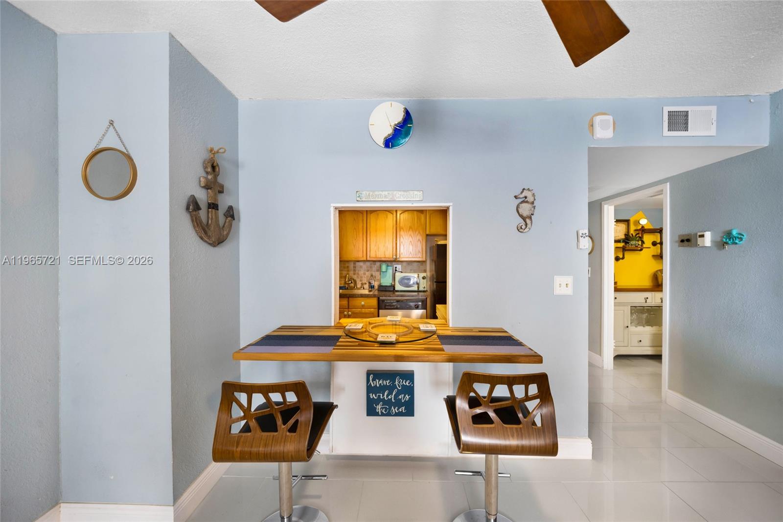 A dining area features a breakfast bar with two wooden stools and a kitchen pass-through — 3180 S Ocean Dr # 607, Hallandale Beach FL 33009, HALLANDALE BEACH, FL