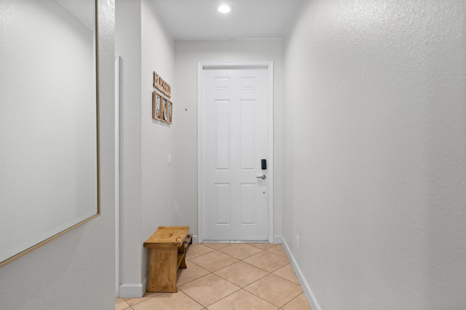 A small entryway features a white door, a wooden bench, and light-colored tile flooring — 9472 SW Merlin Court, Stuart FL 34997, STUART, FL