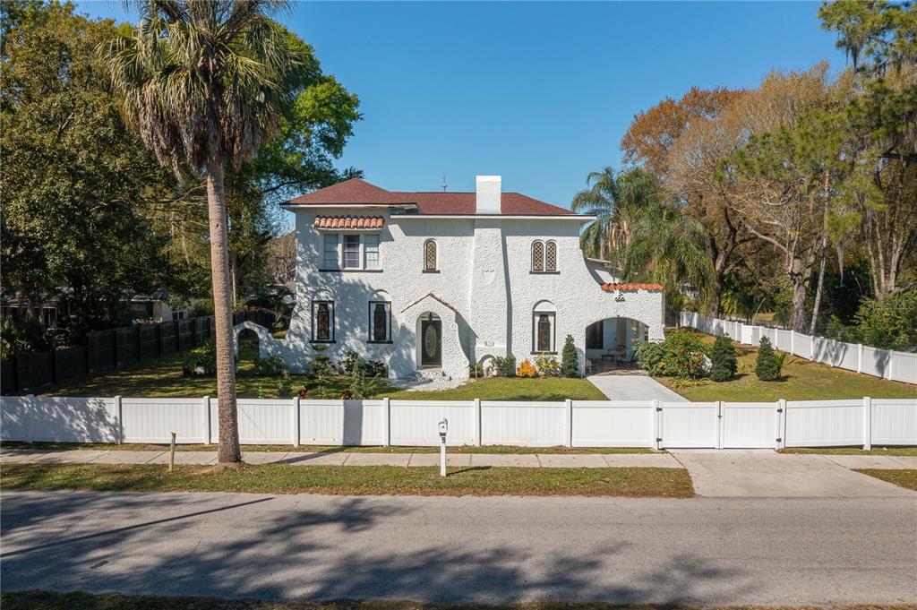A two-story white stucco house with a red roof sits behind a white vinyl fence — 409 21ST STREET SW, WINTER HAVEN, FL