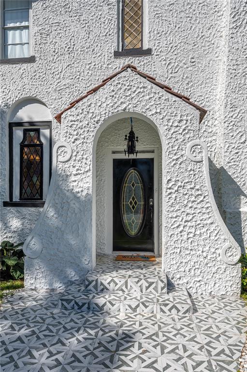 An arched entryway with a black door and decorative scrollwork on a stucco exterior — 409 21ST STREET SW, WINTER HAVEN, FL