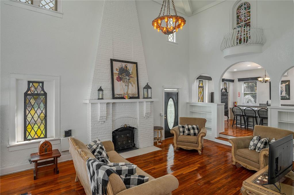 A living room with a tall white brick fireplace, hardwood floors, and a balcony above — 409 21ST STREET SW, WINTER HAVEN, FL