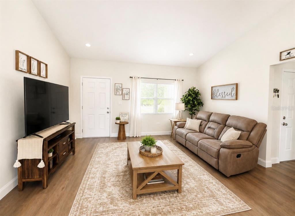 A living room features a brown reclining sofa, a wood coffee table, and a television console — 6486 SW 129TH STREET, OCALA, FL