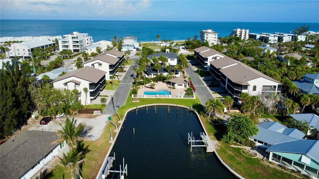 An aerial view shows a waterfront condominium complex with a pool and boat slips — 2729 N BEACH ROAD UNIT 211, ENGLEWOOD, FL