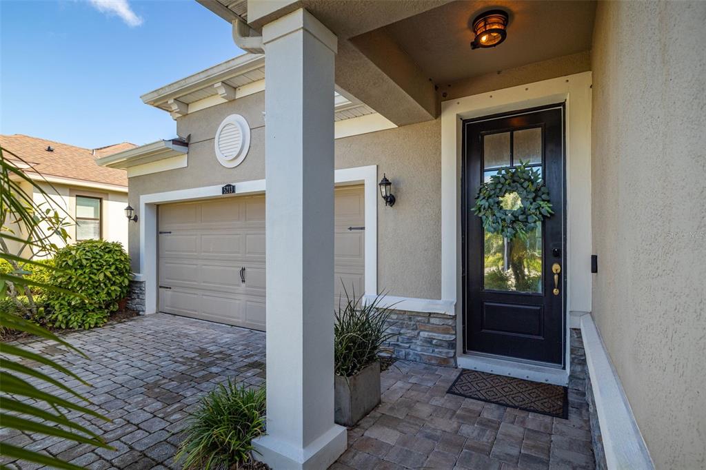 A front entrance with a black door, stone accents, and a paved driveway — 5213 HORIZON COVE, BRADENTON, FL