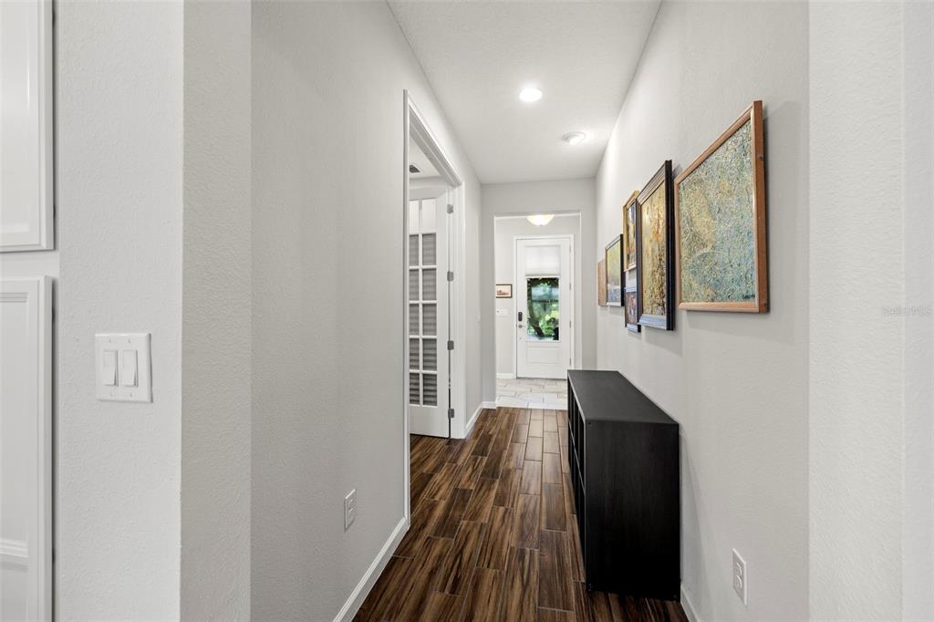 A hallway with wood-look tile flooring, a black console table, and framed artwork on the wall — 5213 HORIZON COVE, BRADENTON, FL