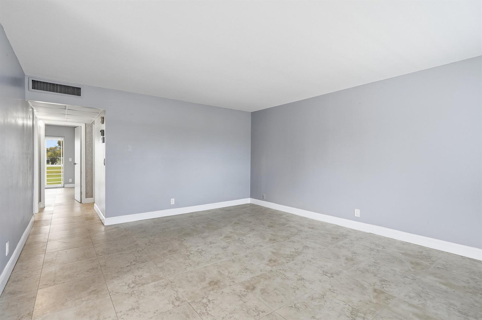 An empty room with light gray walls, tile flooring, and a doorway leading outside — 373 Tuscany G, Delray Beach FL 33446, DELRAY BEACH, FL